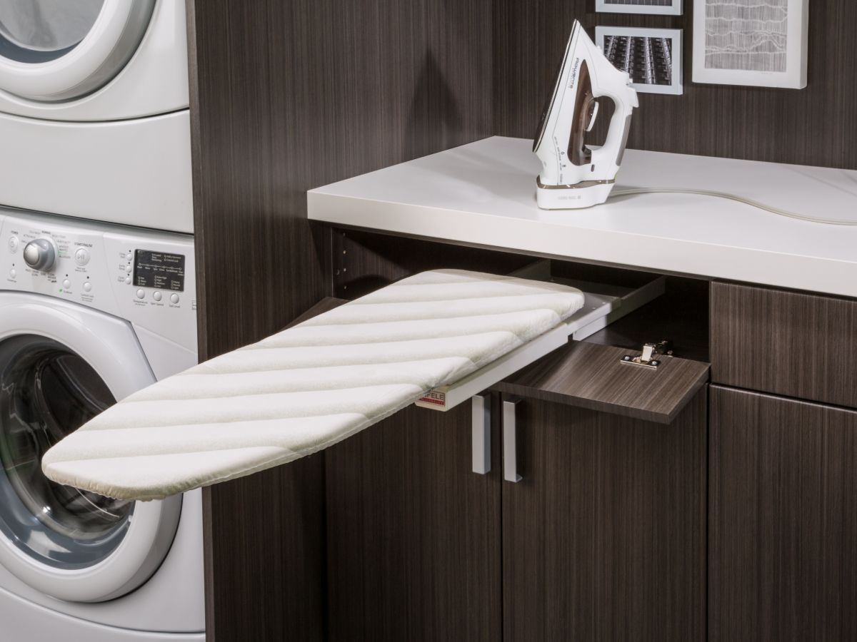 A laundry room with a washer and dryer and an ironing board