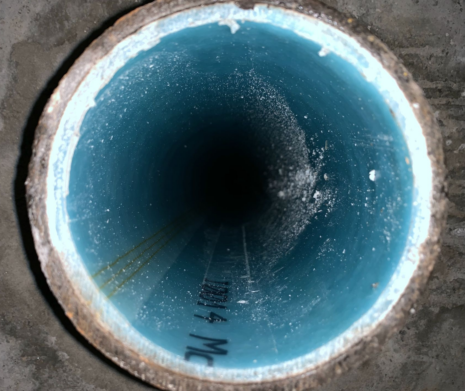 Inside view of a pipe. Teal coating inside, white rim, dark center.