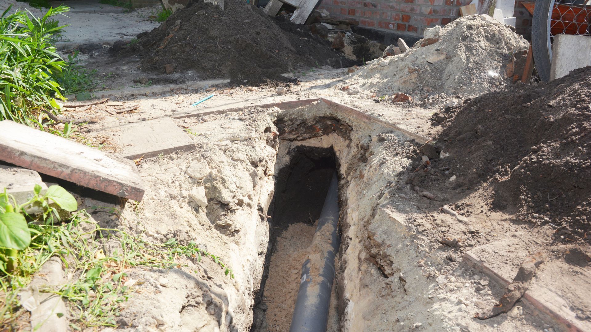 Trench dug for underground pipe, surrounded by dirt and soil.