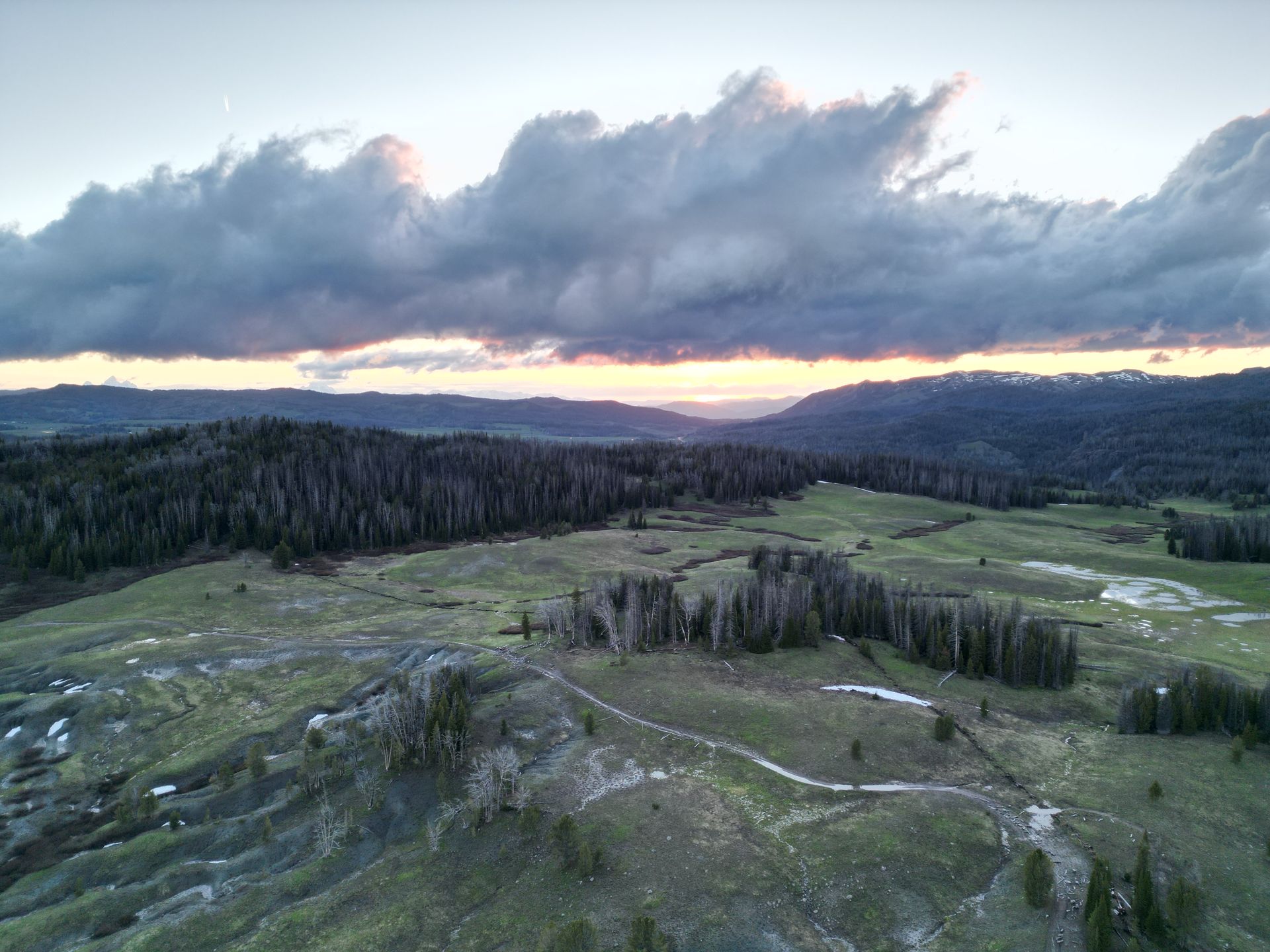 An aerial view of a valley with trees and mountains at sunset.