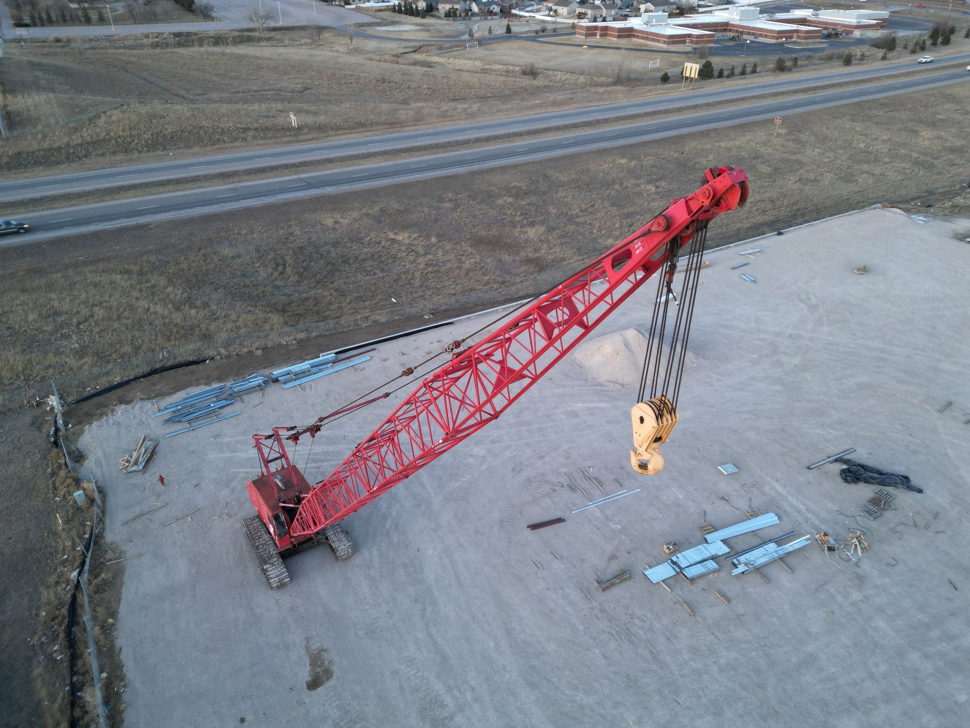 An aerial view of a large red crane in a parking lot.