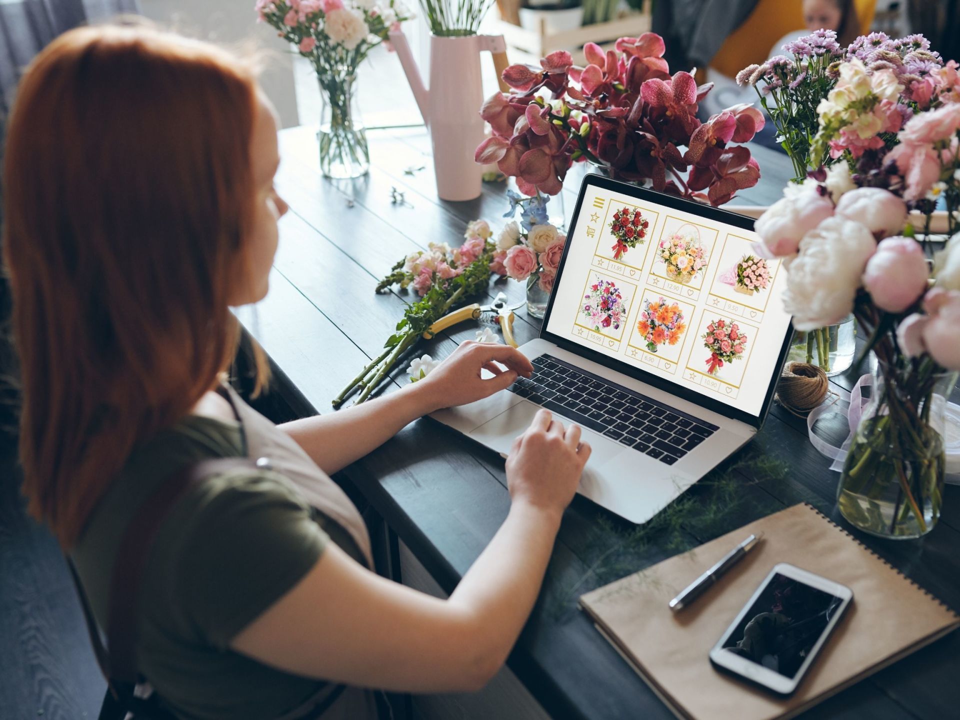 Young lady using laptop to update her florist website