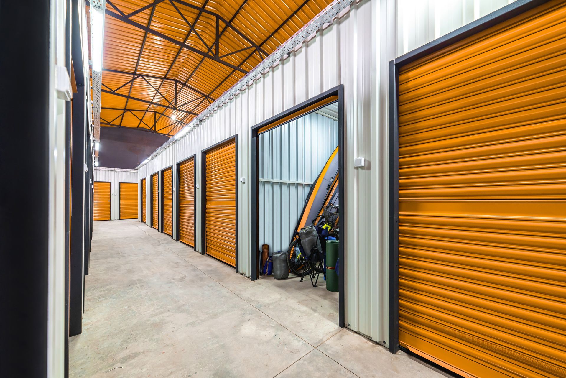 Indoor self-storage units with orange roll-up doors in a secure facility.