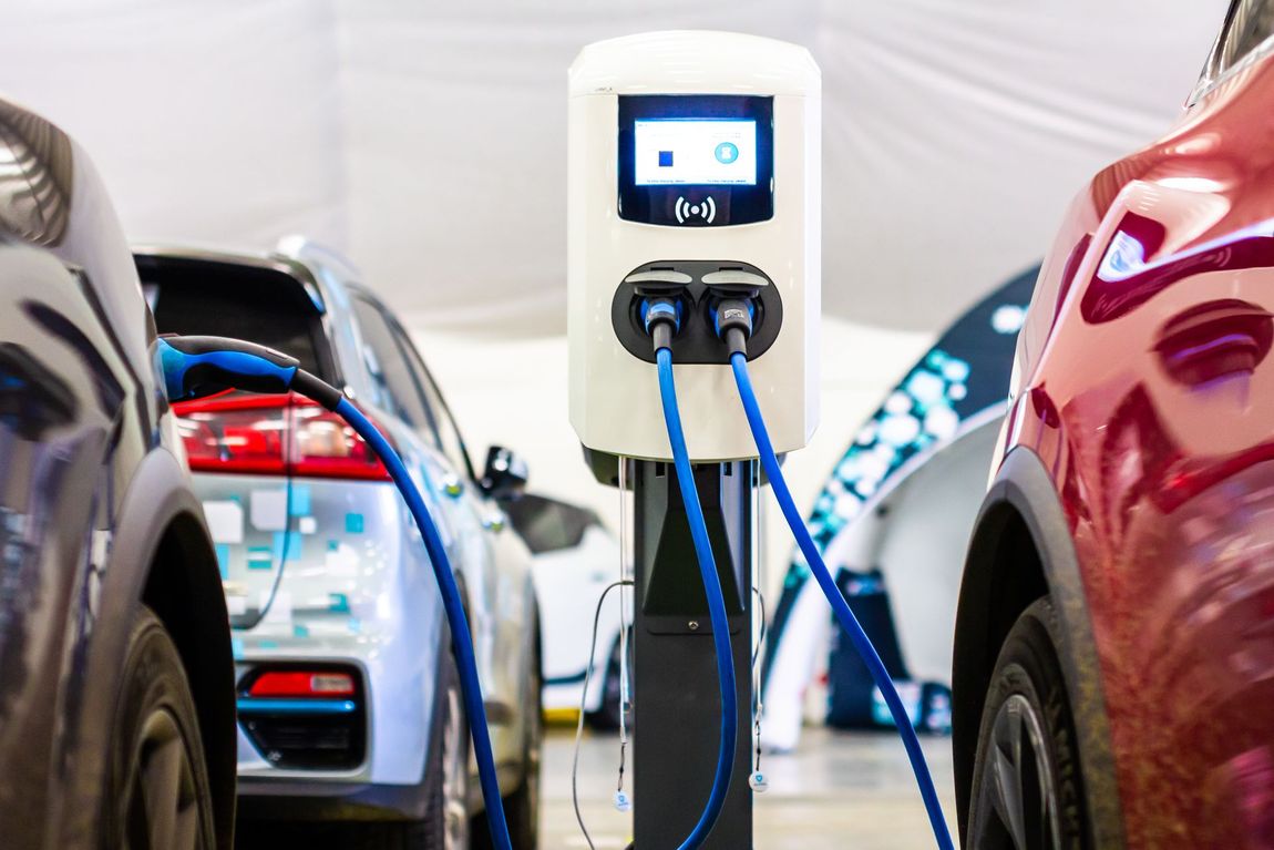 Two electric cars are being charged at a charging station.