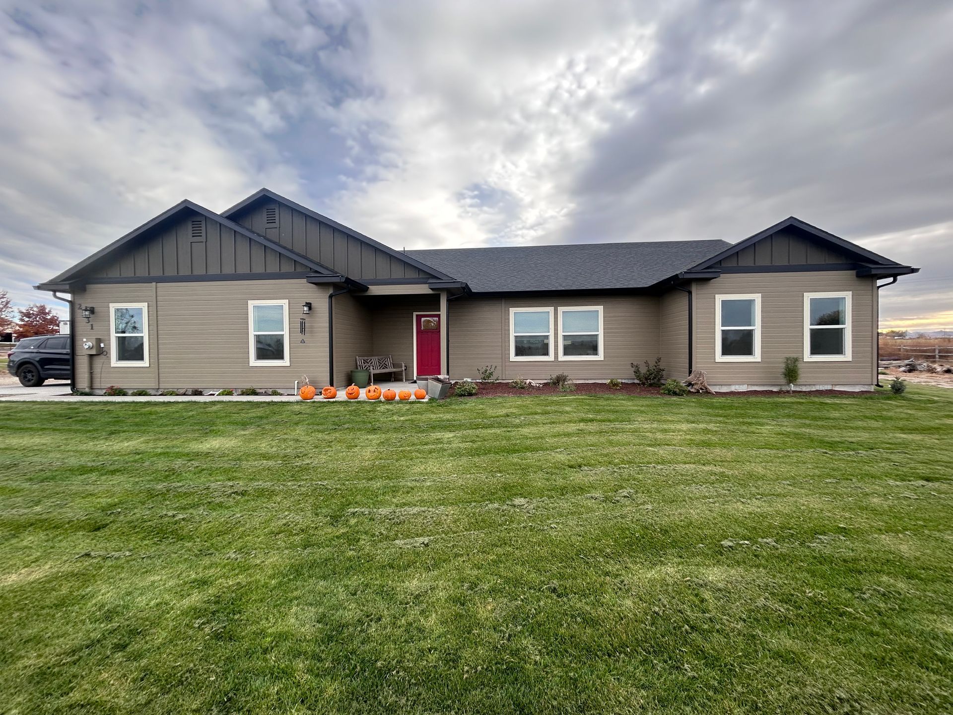 A large house with a lot of windows is sitting on top of a lush green field.