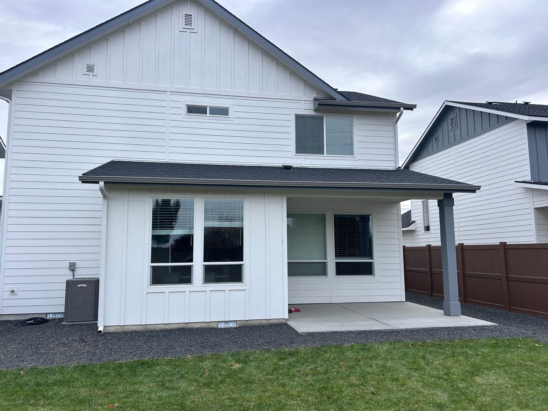 The back of a white house with a porch and a fence