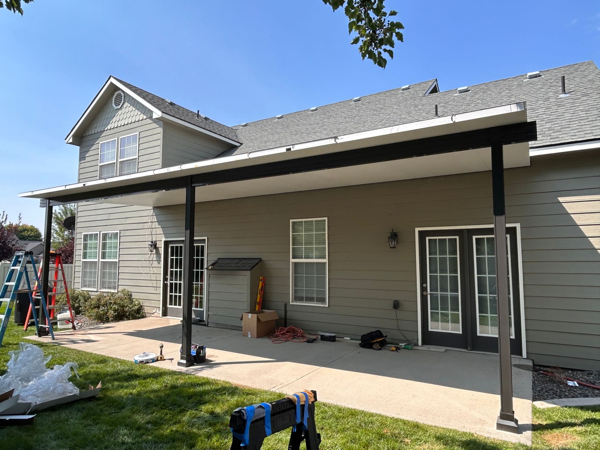 A house with a porch and a roof is being painted.