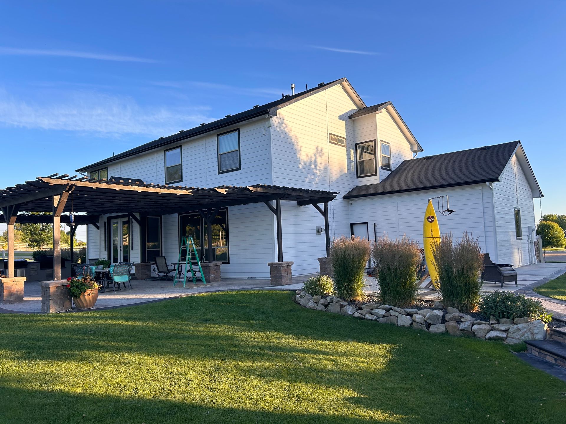 A large white house with a yellow surfboard in front of it.