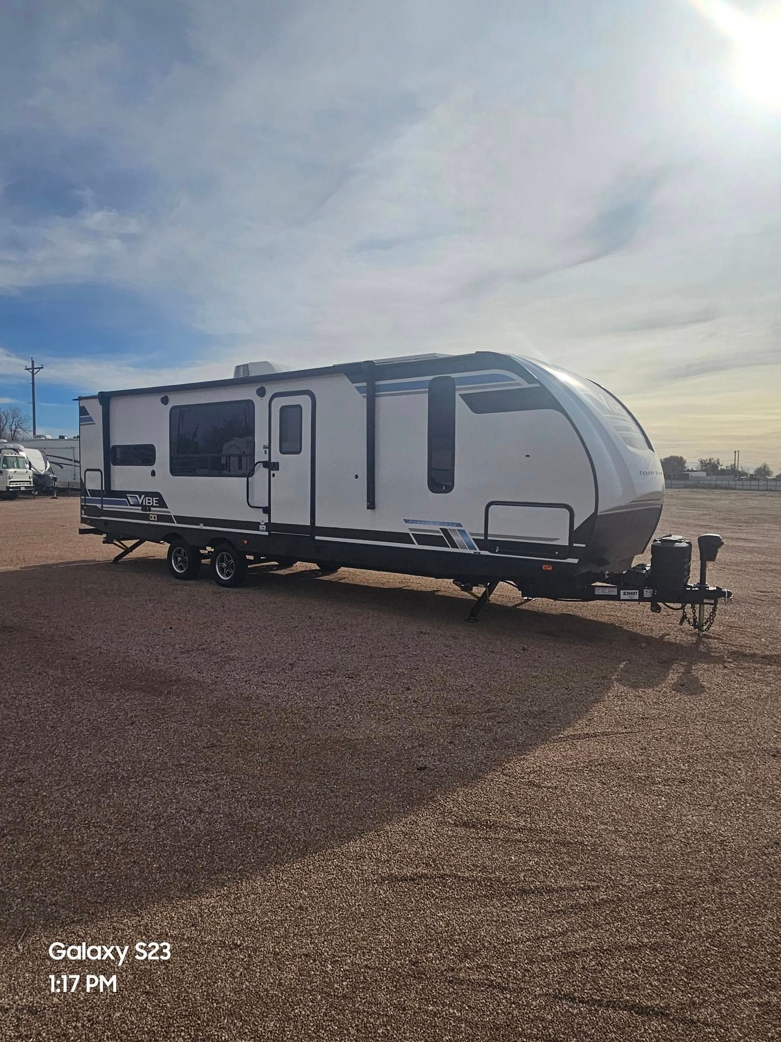 White travel trailer on gravel under a cloudy sky.