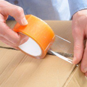 two hands taping a cardboard box shut