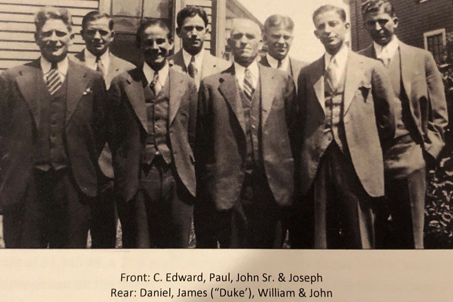Black and white photo of eight men all dressed in suits.