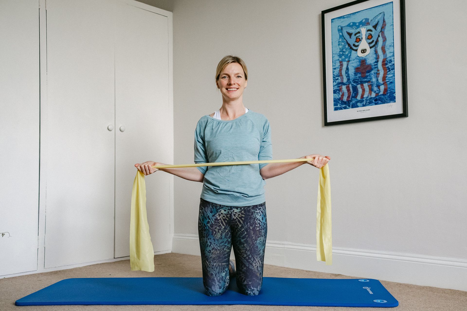 A woman is helping a man stretch his arms on a yoga mat.