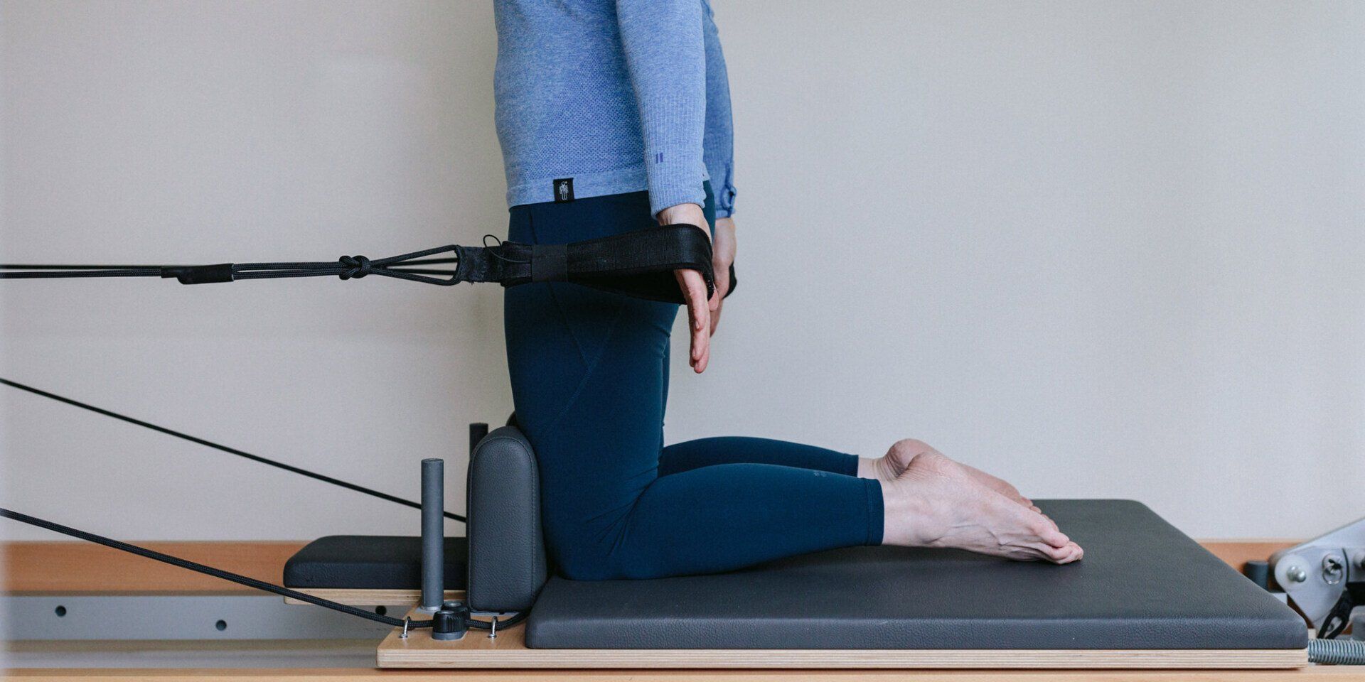 A person is kneeling on a pilates machine.