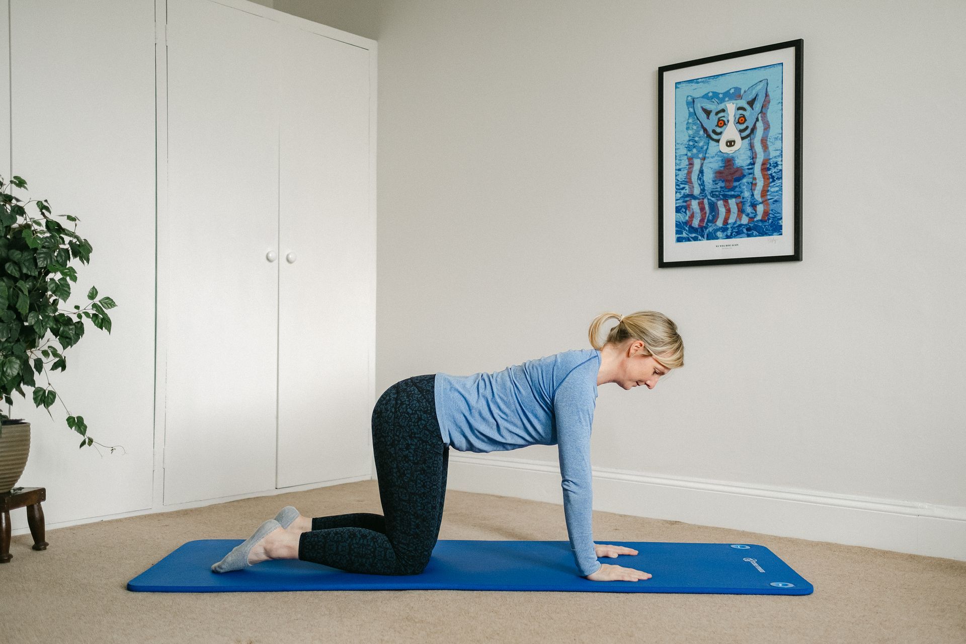 A woman is helping another woman do exercises on a mat.