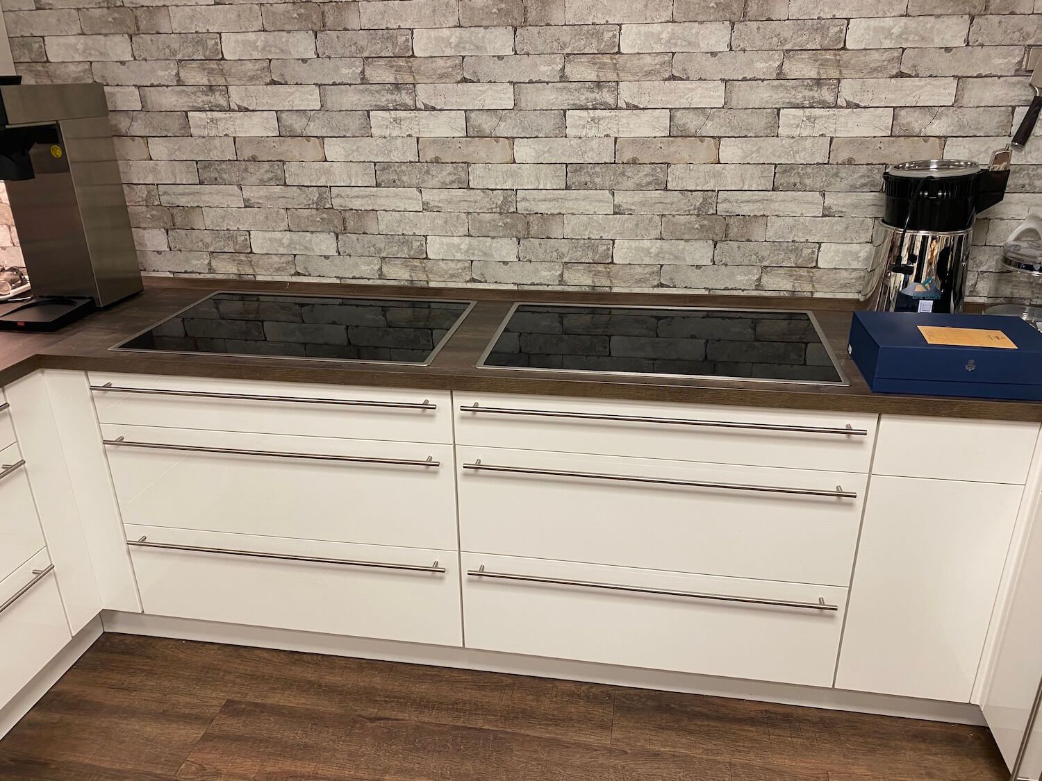 Eine Küche mit weißen Schränken, einem Herd mit Backofen und einer Ziegelwand.