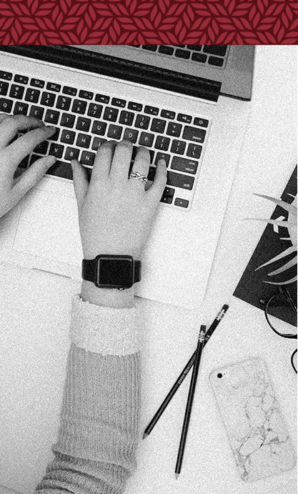 A person is typing on a laptop computer while wearing a watch.