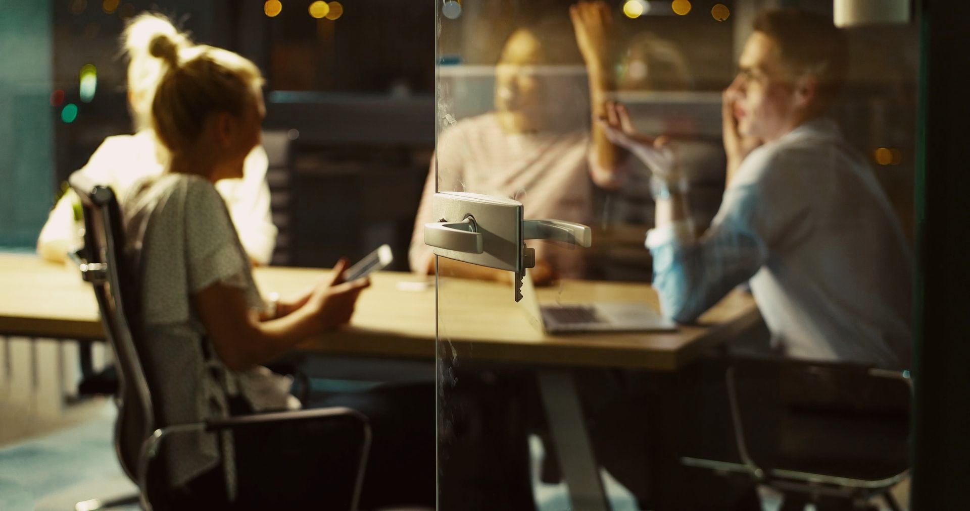 a group of people are sitting around a table behind a glass door