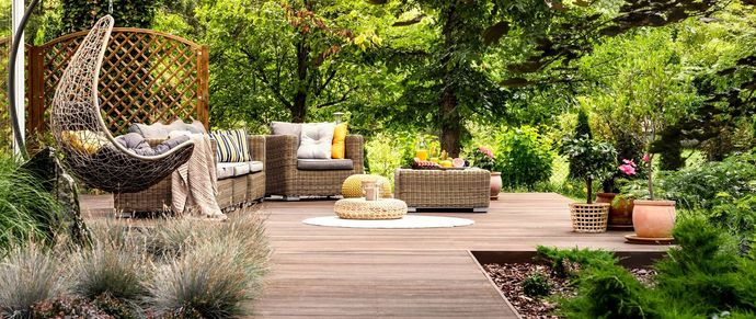 Outdoor patio with woven furniture and lush greenery.