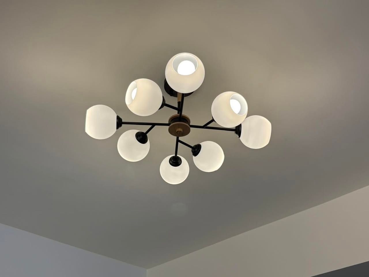 A modern, black and gold ceiling light with white spherical bulbs.