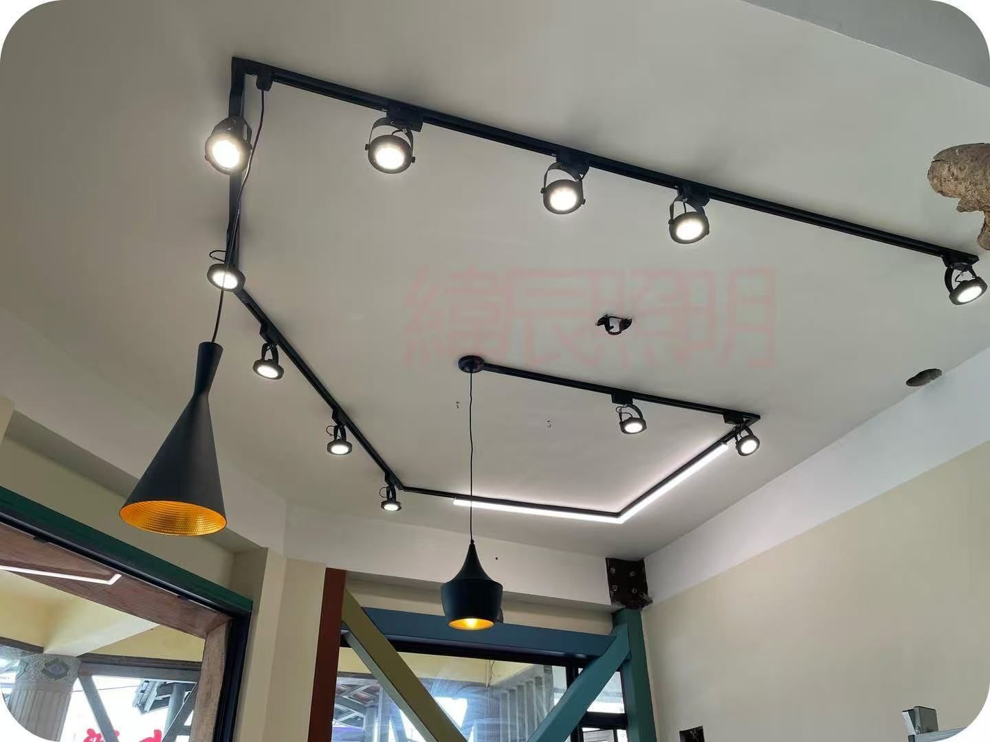 Black track lighting system on a white ceiling with several spotlights illuminating the room.