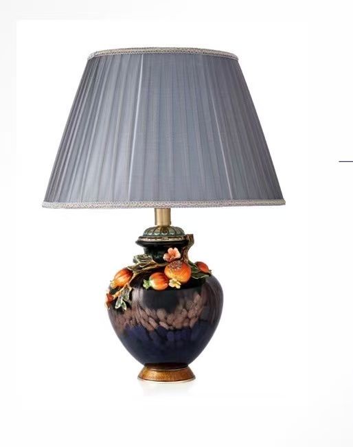 Blue ceramic table lamp with gray pleated shade and fruit-themed base.
