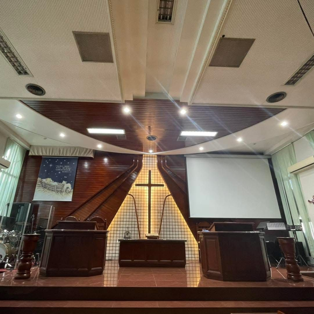 Interior of a church sanctuary with a cross on the altar, podiums, and a screen.