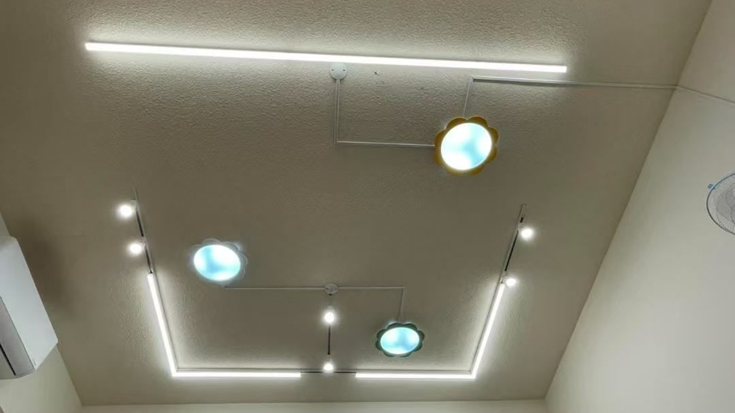 Ceiling with modern lighting design: linear lights, spotlights, and blue/gold round fixtures.
