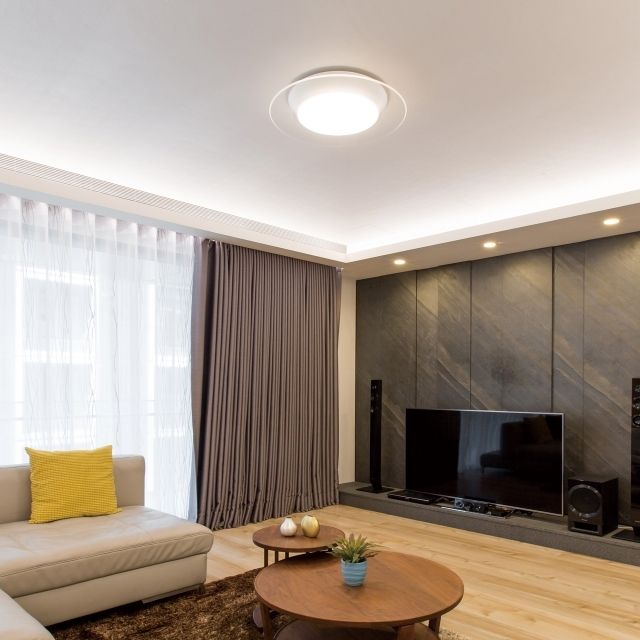 Modern living room with neutral colors, a large TV, and round coffee tables.