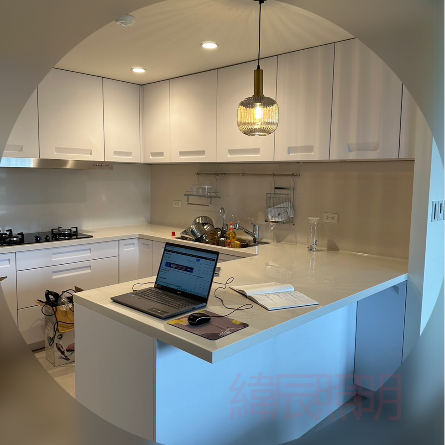 Modern white kitchen with island, overhead cabinets, and laptop.