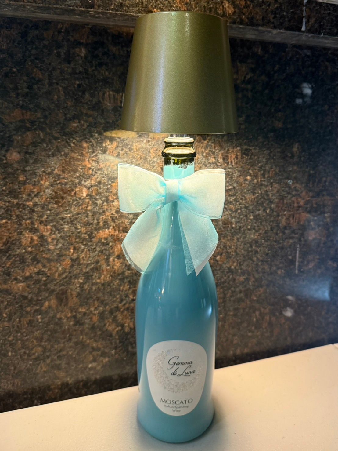Blue bottle lamp with a teal bow and green shade.