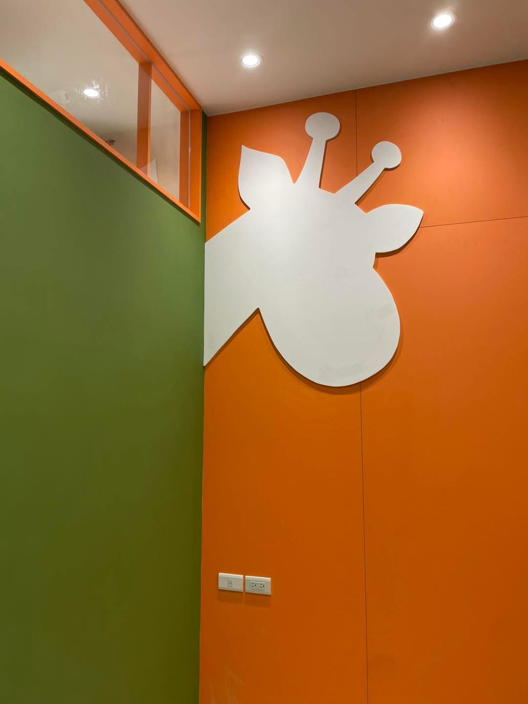 Green and orange walls with a white giraffe head.