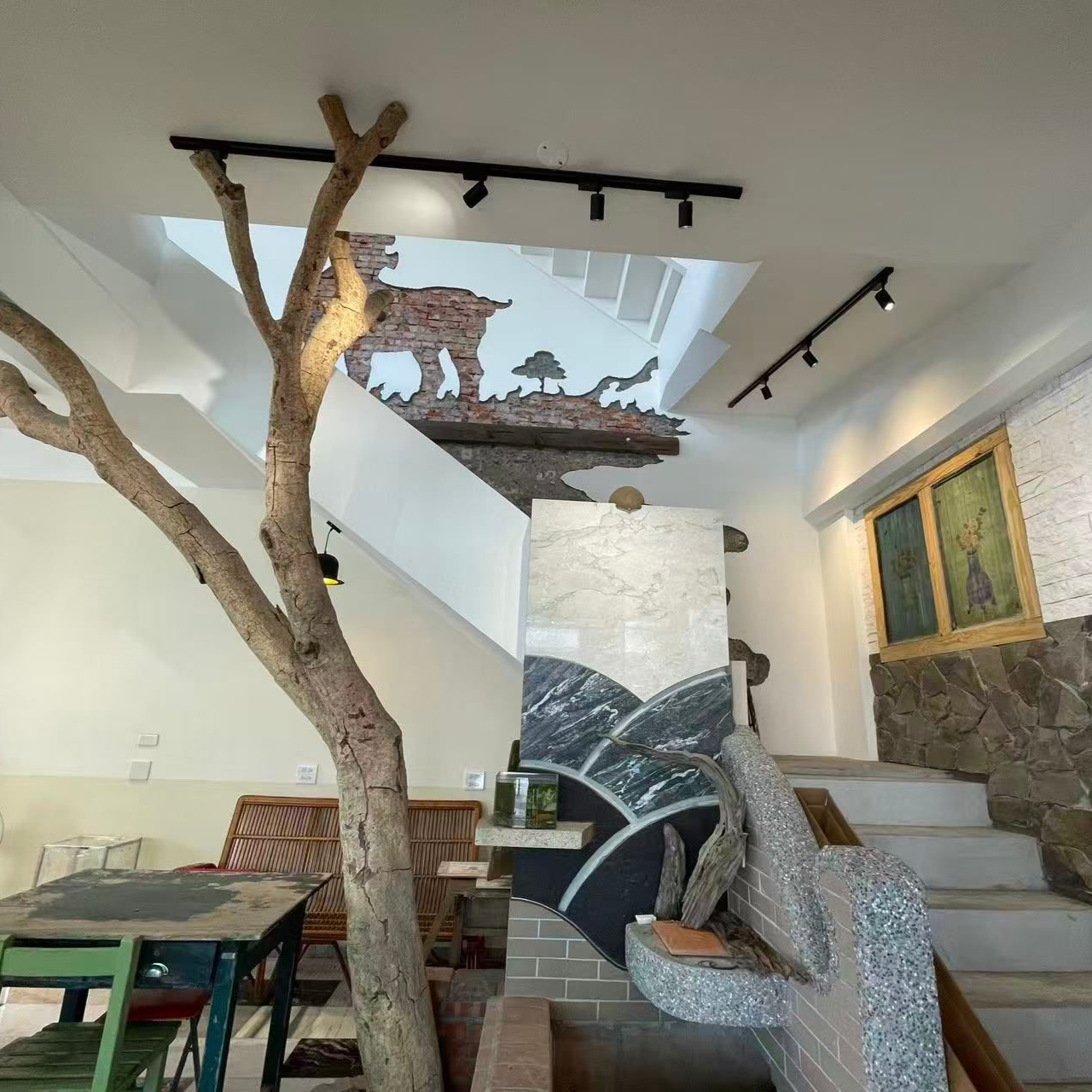 Interior with tree, staircase, mural of deer, and artistic wall features.