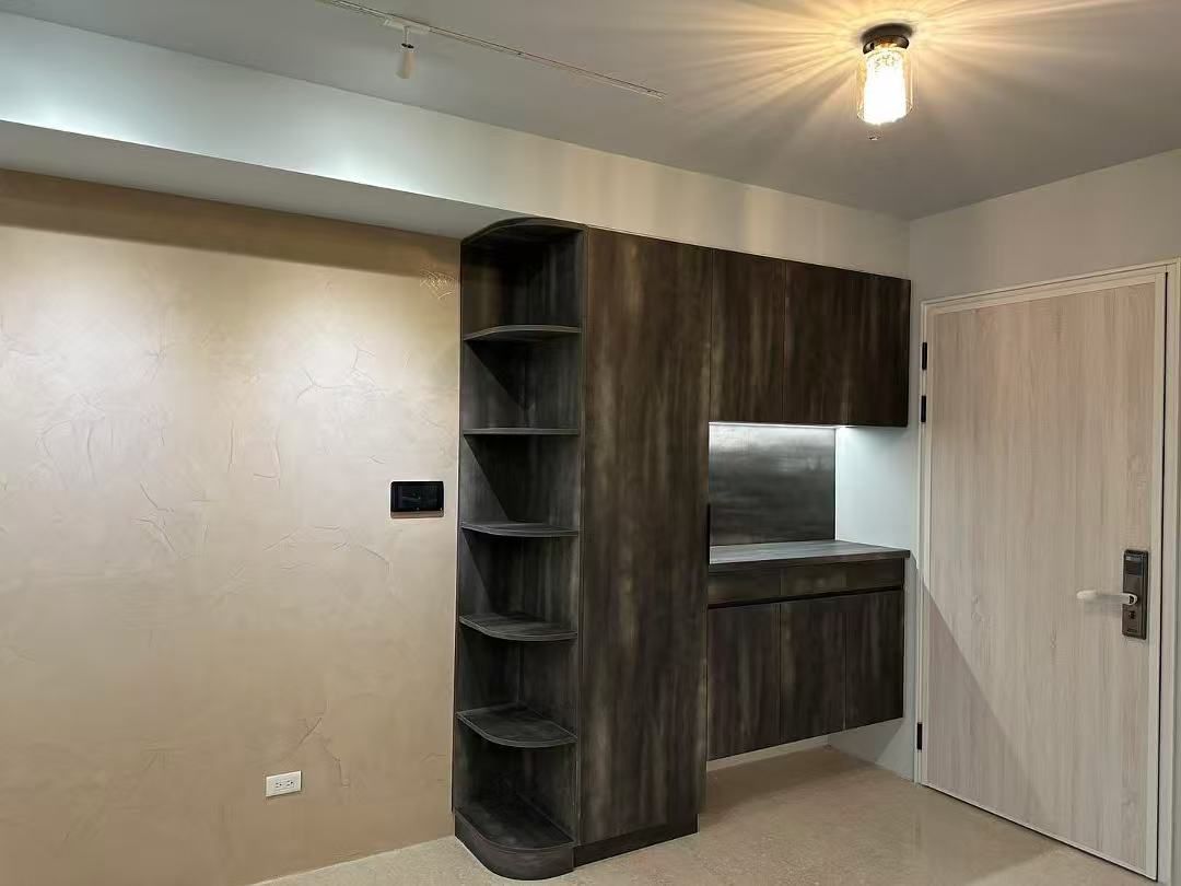 Dark wood built-in shelving and cabinets with a neutral-toned wall and a closed door.