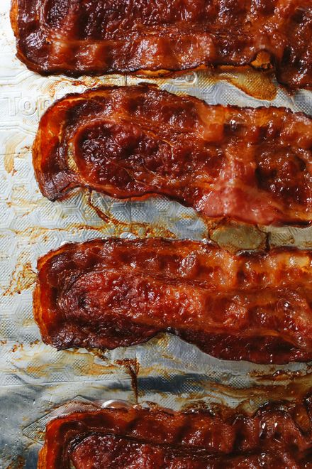 Several strips of crispy, dark brown glazed bacon arranged on a piece of aluminum foil.