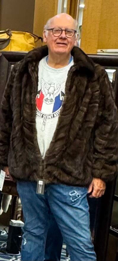 Smiling man in a blue shirt holds books in a used bookstore, 