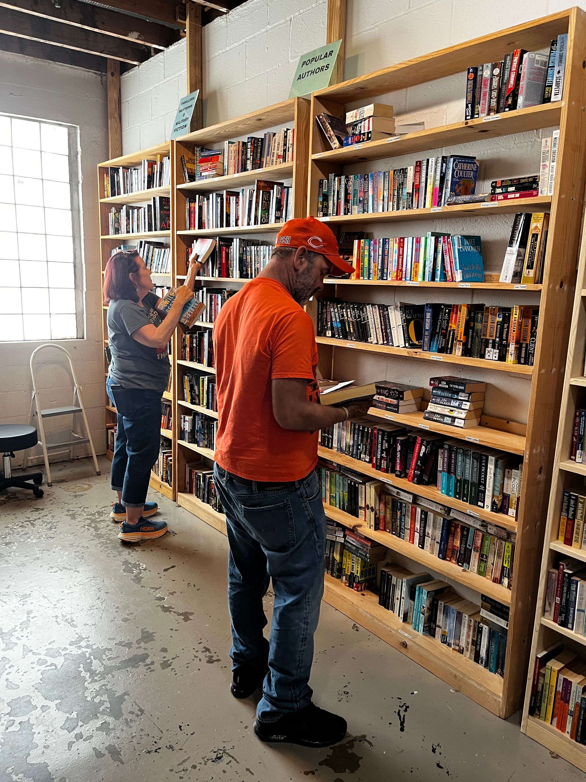 Man and woman standing in front of bookshelves choosing books.