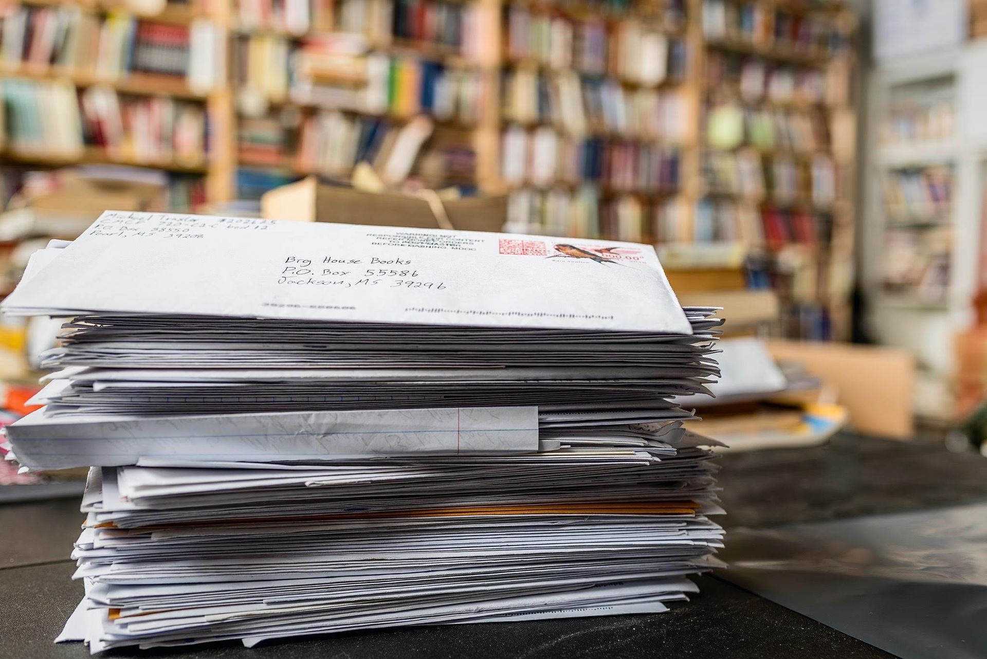 Woman and two girls smile, holding books and a notebook in a bookstore. Shelves of books are in the background.