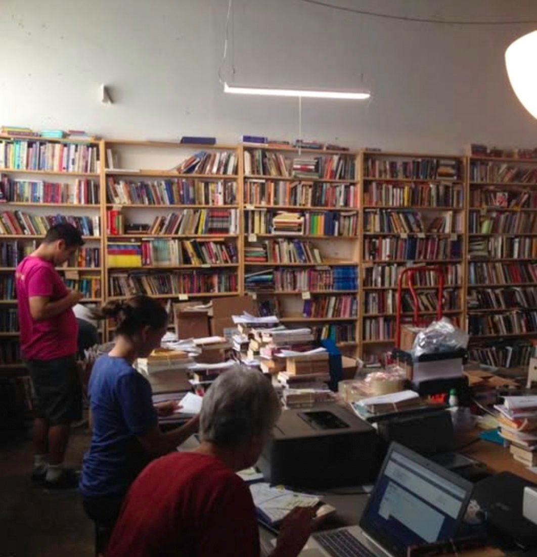 People at work behind a desk surrounded by bookshelves in a bookstore.
