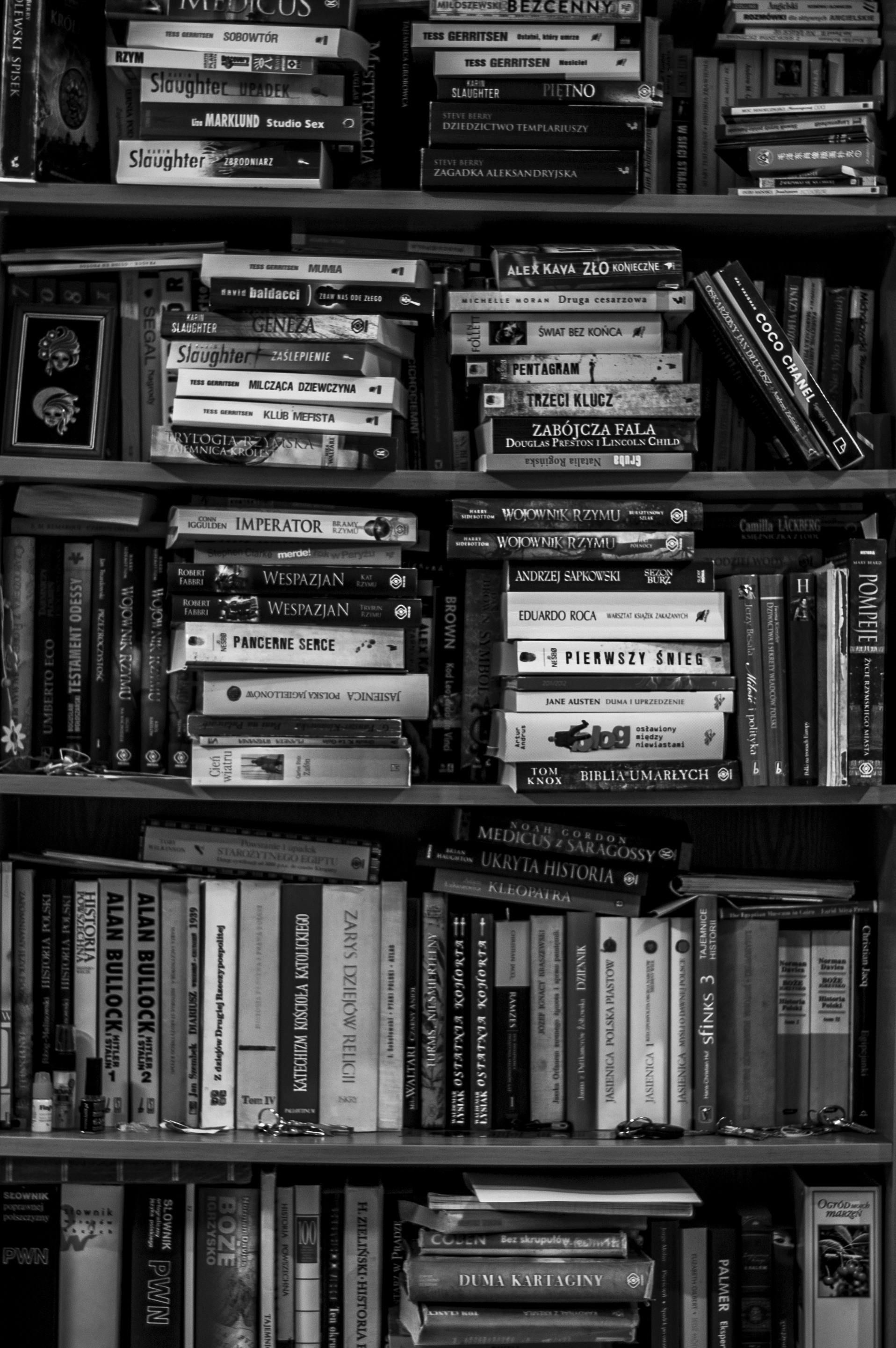 Bookshelves overflowing with books; black and white.