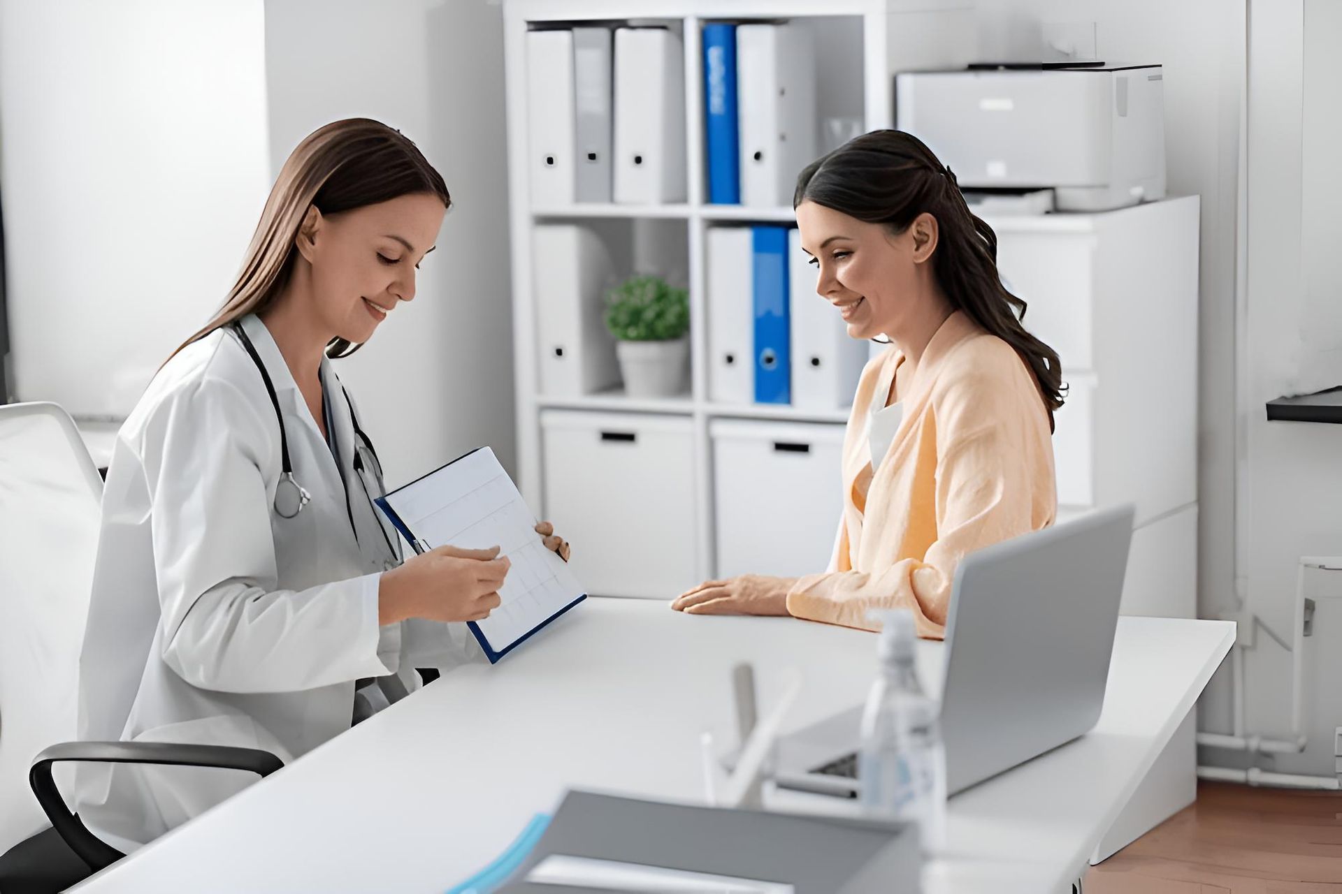 A Doctor is Talking to a Patient Who is Sitting at a Desk With a Laptop — Eastcoast Women's Centre in Emerald, QLD