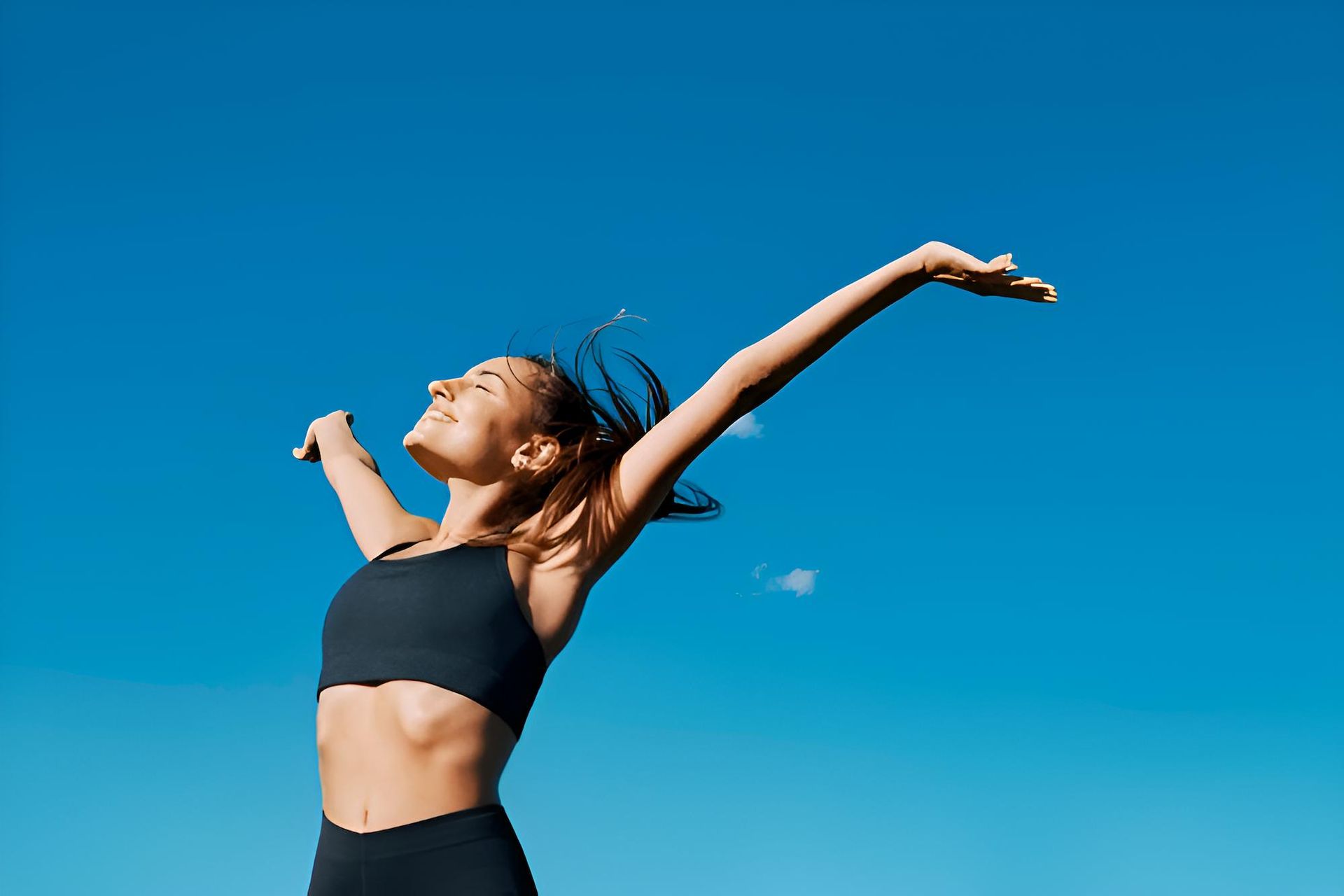 A Woman is Standing With Her Arms Outstretched in Front of a Blue Sky — Eastcoast Women's Centre in Townsville, QLD