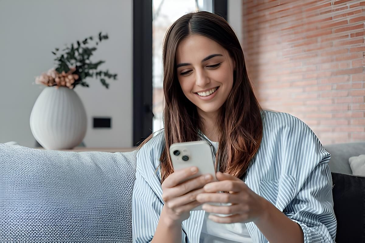 A Woman is Sitting on a Couch Looking at Her Cell Phone — Eastcoast Women's Centre in Rockhampton, QLD