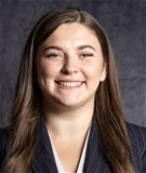 A woman in a suit is smiling for the camera.