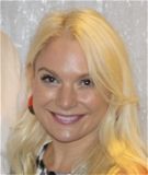 A woman wearing hoop earrings and a white shirt is smiling for the camera.