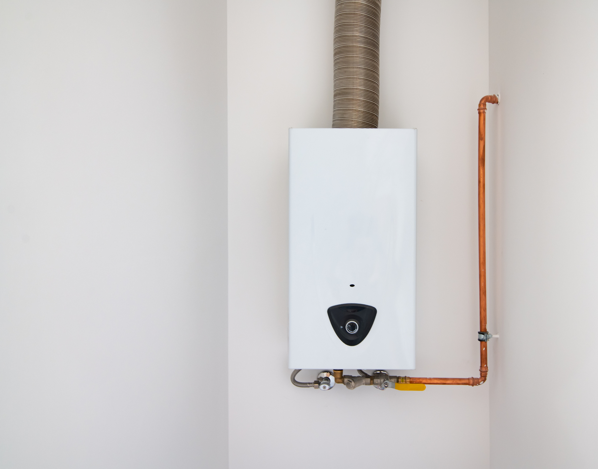 White wall-mounted water heater with copper pipes and a vent.