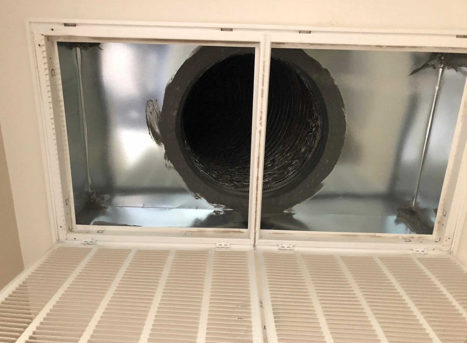 Rectangular air duct opening with a filter and a round duct visible.