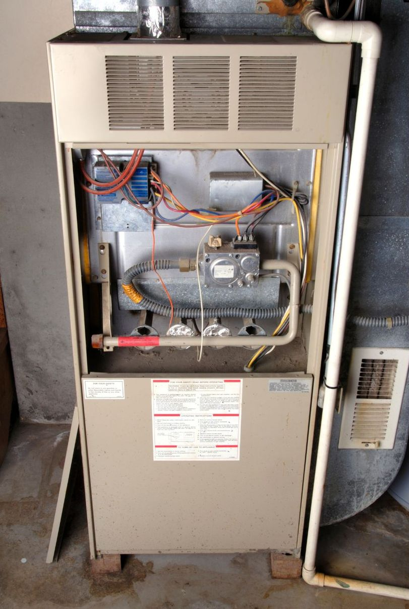 Beige furnace with open door, showing internal components and wiring.