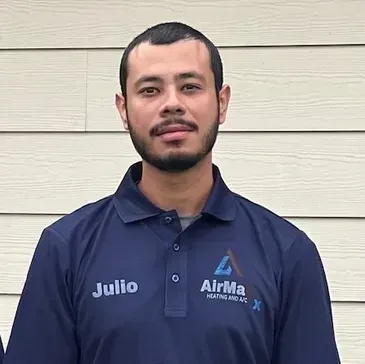 Man in blue polo shirt with company logo, standing in front of beige siding.