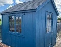 a blue shed with a black roof and a window .