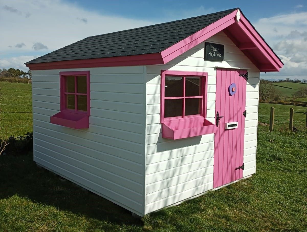 a white shed with a pink door and windows
